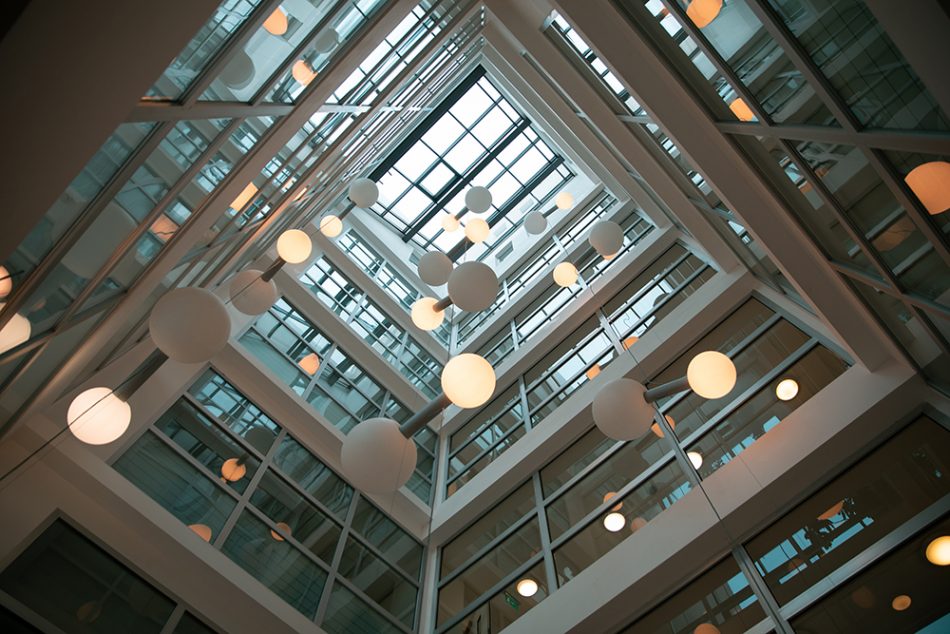 Interiørdesignet til innsiden av en moderne bygning med glasstak som slipper inn lys og mange hengende runde lamper