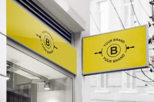 Et gult skilt over et butikkvindu med teksten "your brand", illustrasjon av en visuell identitet