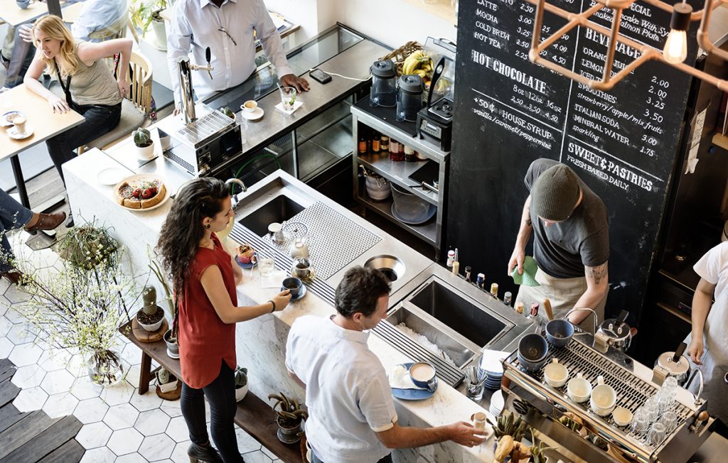 Personer som står i en kaffebar med en barista som står og jobber, øke omsetning i butikk